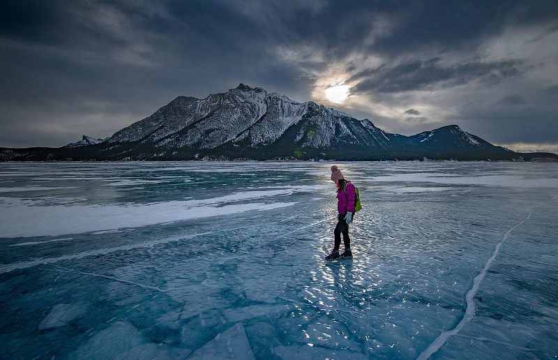 在加拿大的落基山房子里，一个女人在冬天站在冰湖上图片素材