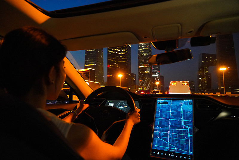 夜晚按屏幕地图开车的青年女人图片素材