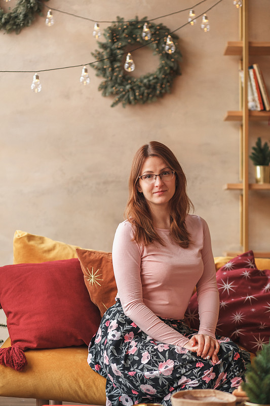 俄罗斯，坐在沙发上装饰圣诞节的女人图片素材