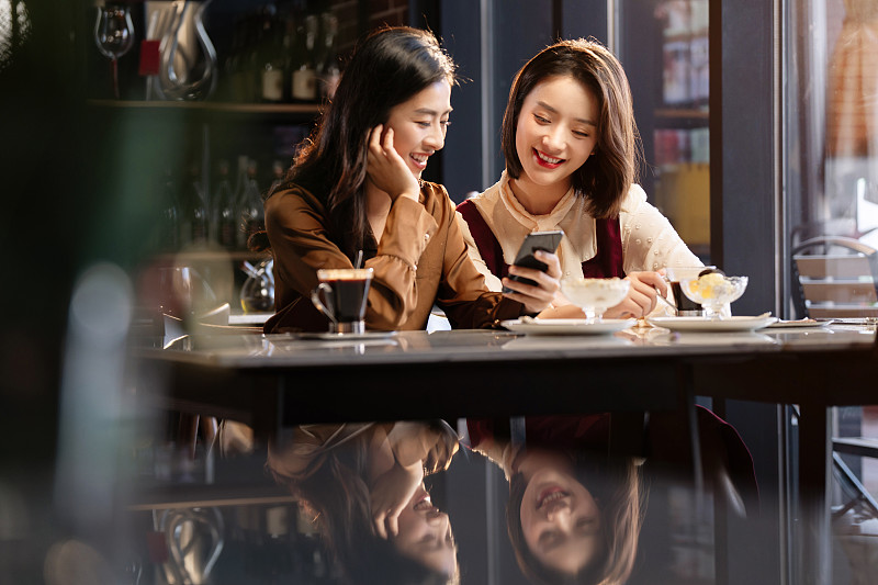 年轻闺蜜在咖啡馆使用手机图片下载