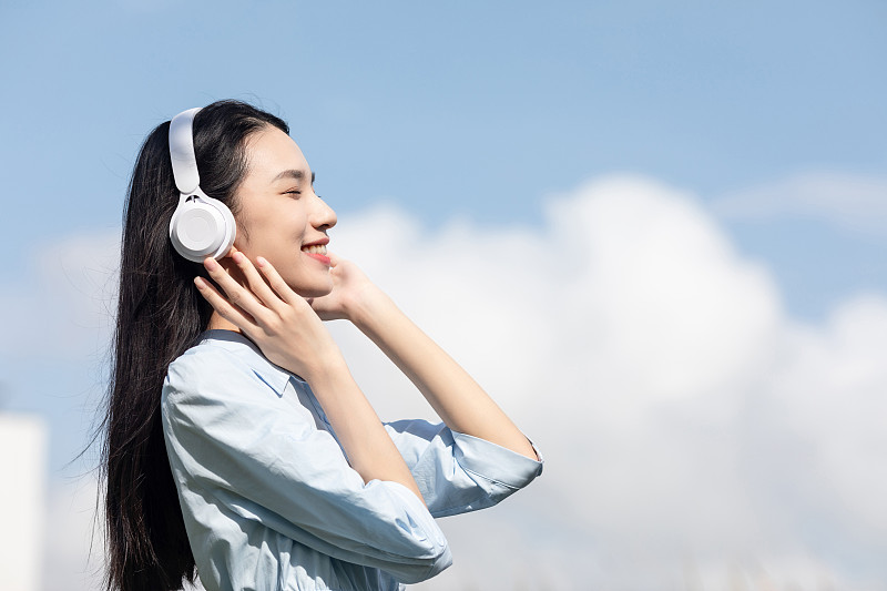 蓝天白云下一名年轻女性在听音乐图片下载