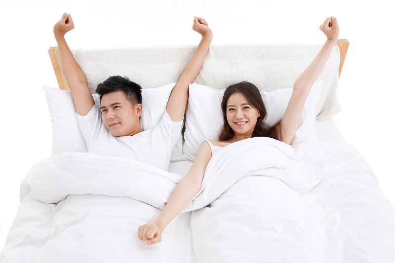 青年夫妇躺在卧室的床上准备起床图片下载