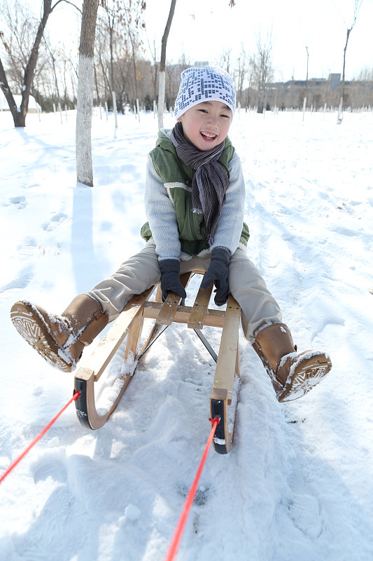 小男孩坐在雪橇上滑雪图片素材