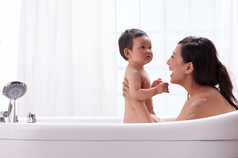 母亲和婴儿坐在浴缸中洗澡图片下载
