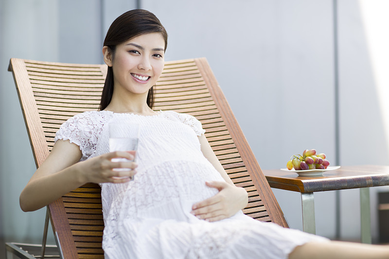 孕妇靠在躺椅上喝水图片下载