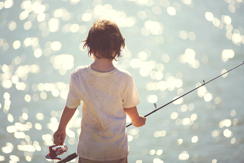 男孩(6-7)拿着鱼竿的后视图图片下载