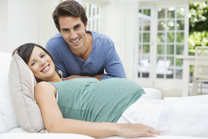 一个男人坐在躺在床上的孕妇旁边图片下载