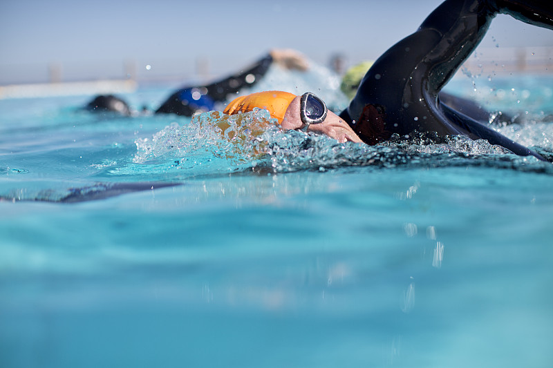 穿着潜水衣的铁人三项运动员在游泳池里溅水花图片下载