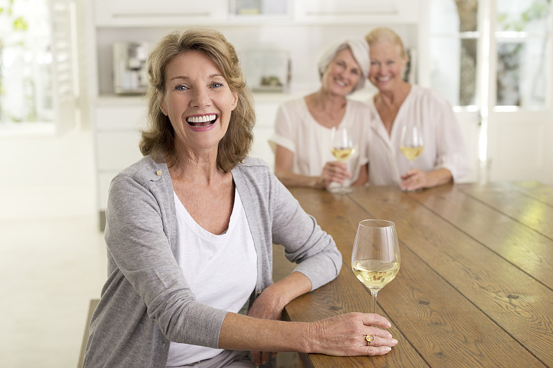微笑的老年妇女喝白葡萄酒的肖像图片下载