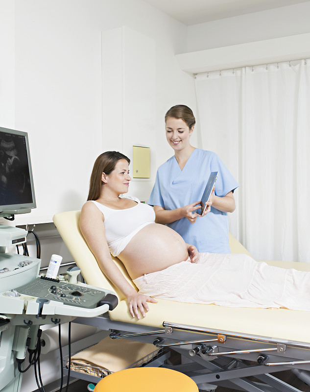 医生使用平板电脑向孕妇展示超声波扫描图图片下载
