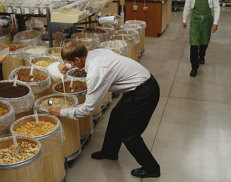一个男人在商店的大箱子里吃麦片图片素材