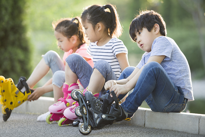 儿童坐在路边穿直排轮鞋图片下载