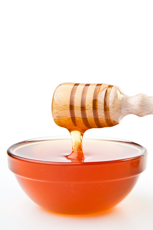 蜂蜜勺水平地在白色的背景下滴下一滴蜂蜜图片素材