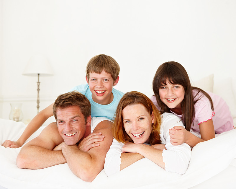 幸福的父母和他们的孩子躺在床上图片下载
