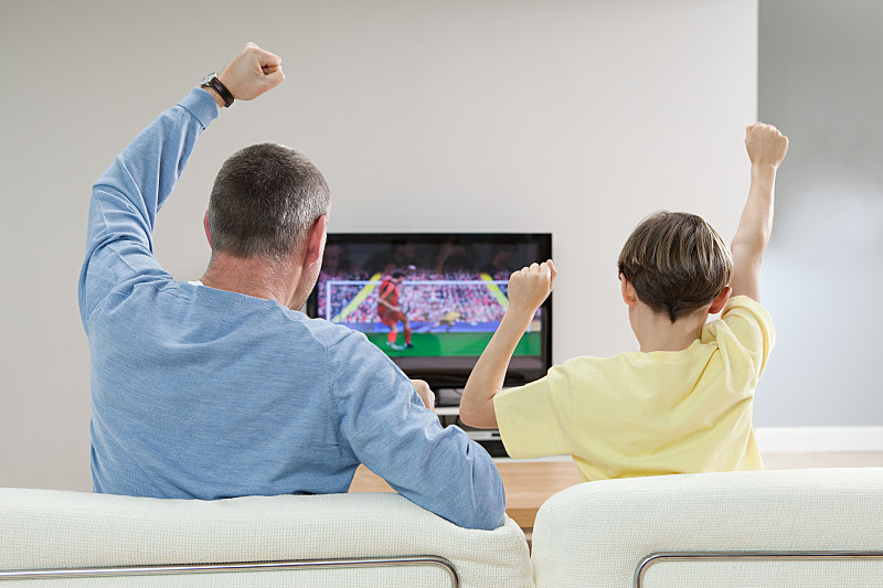父子俩在电视上看足球比赛图片下载