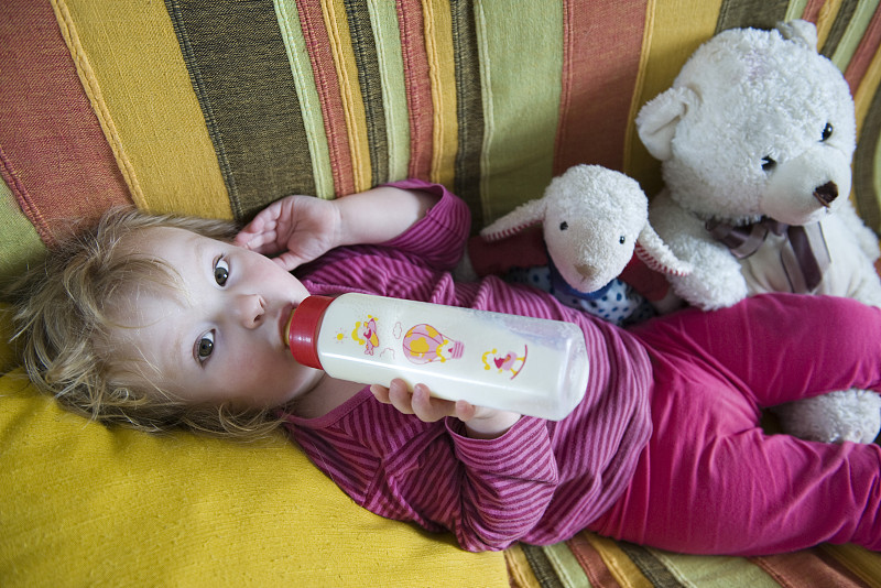 女婴躺着，喝着奶瓶里的牛奶图片下载