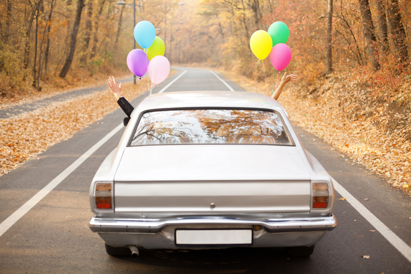 一对新婚夫妇把气球绑在他们的汽车上图片素材