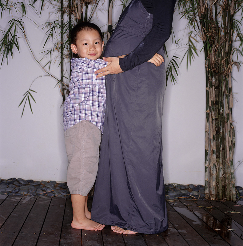 儿子(6-7)拥抱怀孕的母亲，肖像图片下载