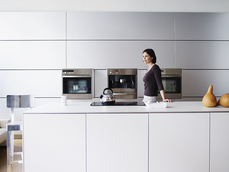 女人站在家庭厨房，侧视图图片下载