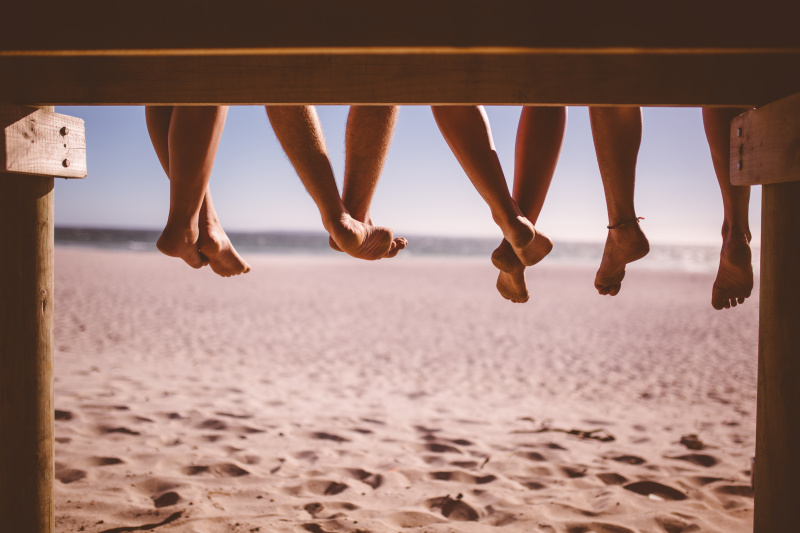 朋友们的腿一起坐在海边的木板路上图片下载