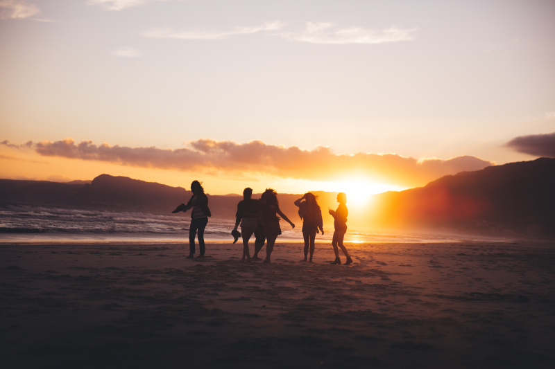 日落时分，沙滩上跳舞的青少年朋友的剪影图片下载