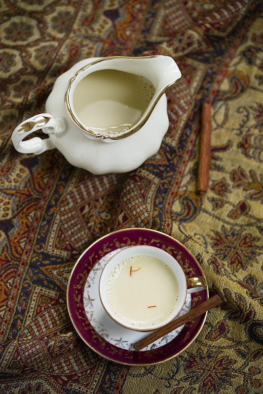牛奶壶和小咖啡杯豆浆，加藏红花和肉桂在布上调味图片下载