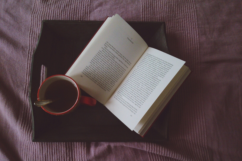 上图为床上的黑咖啡杯，打开的书图片素材