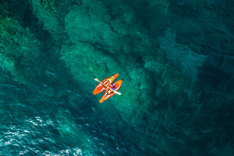 航拍的两个女孩练习皮划艇在一个天堂的地方，在美丽和透明的蓝色海水的夏天的布拉瓦海滩。图片素材