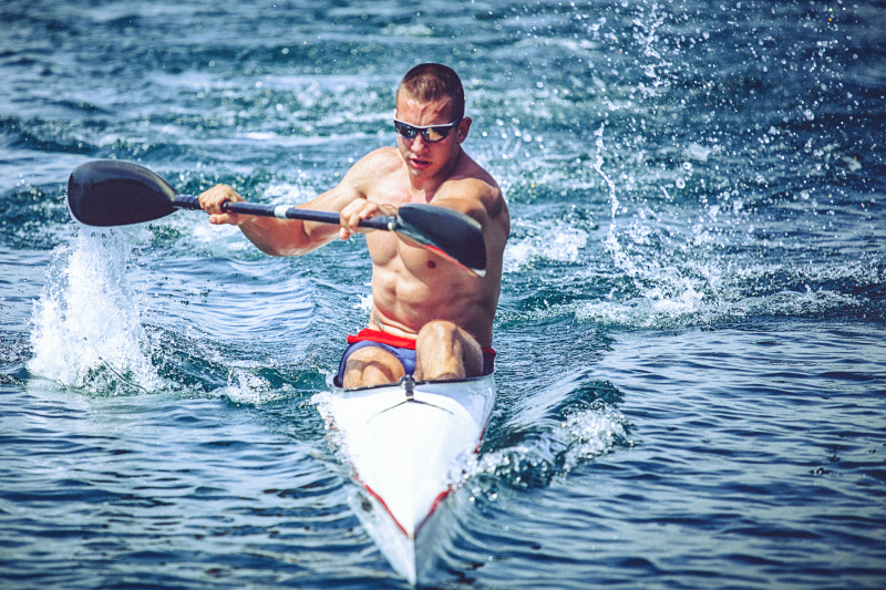 年轻的肌肉男子在皮划艇冲刺训练在静水。图片下载