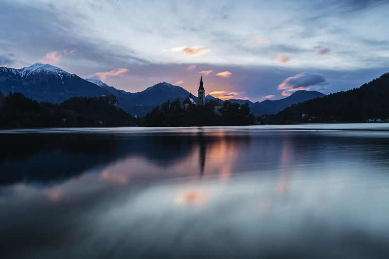 教堂的塔楼和日出的天空倒映在静静的湖面上图片下载