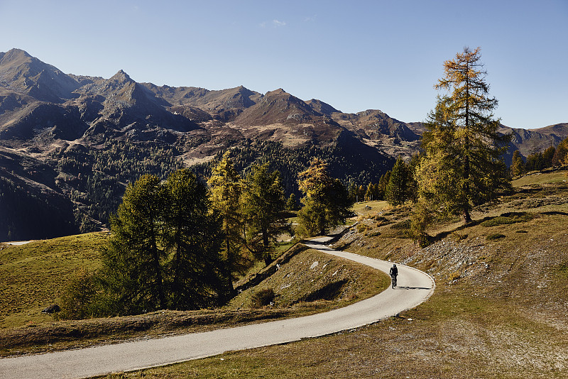 骑自行车的人在路上与山脉的距离，瓦莱州，瑞士图片下载