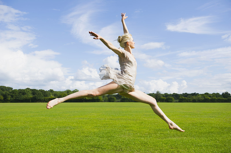 白种芭蕾舞演员在田野里跳跃图片下载