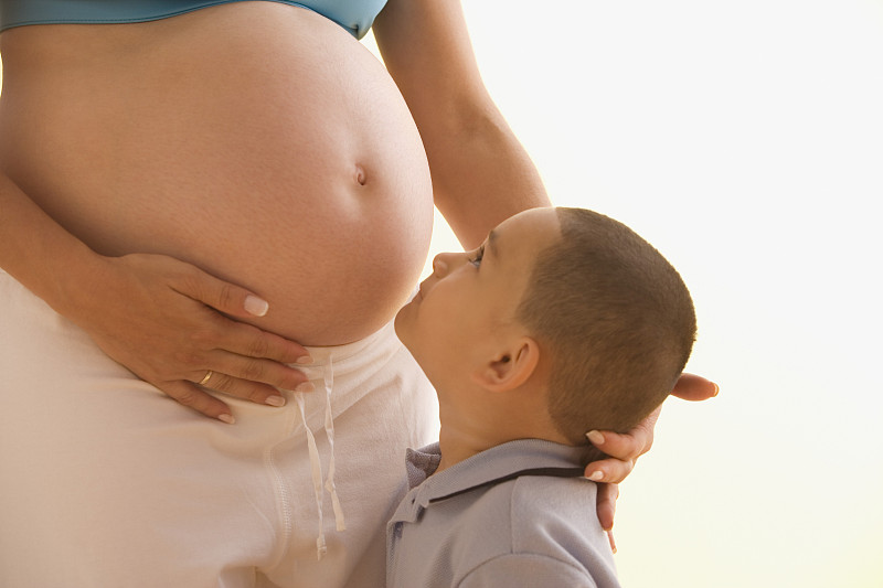 小男孩正在检查他怀孕的母亲的肚子图片下载