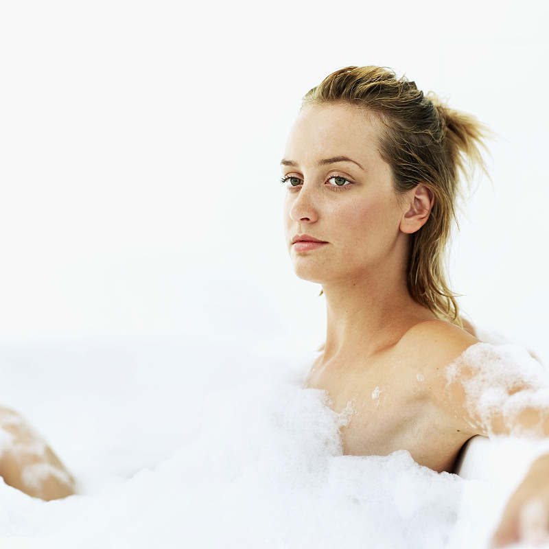 一个年轻女子坐在泡泡浴中的侧影图片下载
