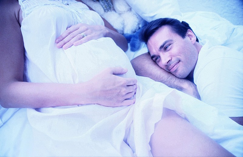 一个男人躺在他怀孕的妻子旁边的高角度特写图片下载