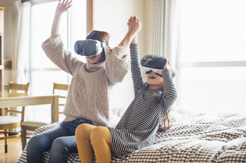 母女俩在卧室里戴着虚拟现实眼镜玩游戏图片下载