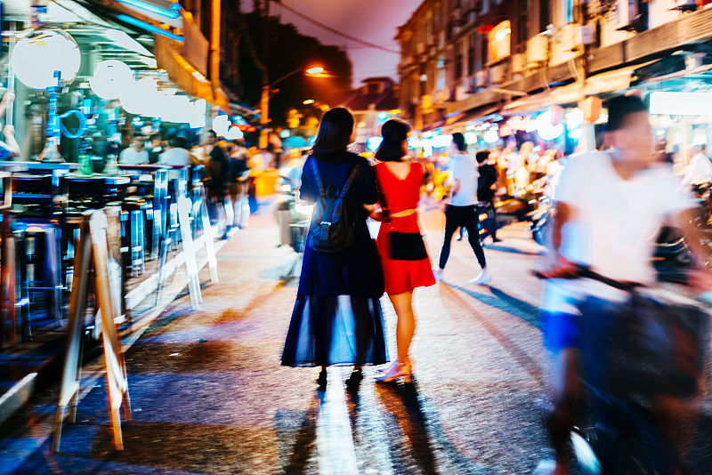 妇女站在照明街道的后视图图片素材