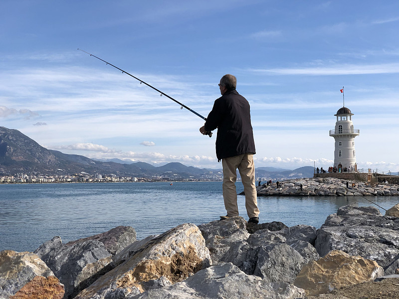 渔夫在灯塔附近钓鱼图片素材