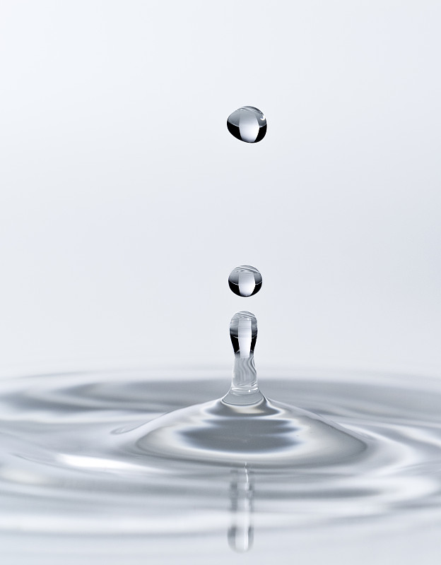 一组水滴悬在空中，落在一个白色背景的水面上。图片下载