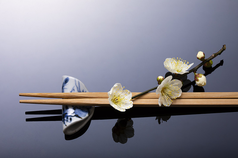 初春的梅花带着一种波浪形锈色的气息。餐桌上装饰着筷子。图片下载