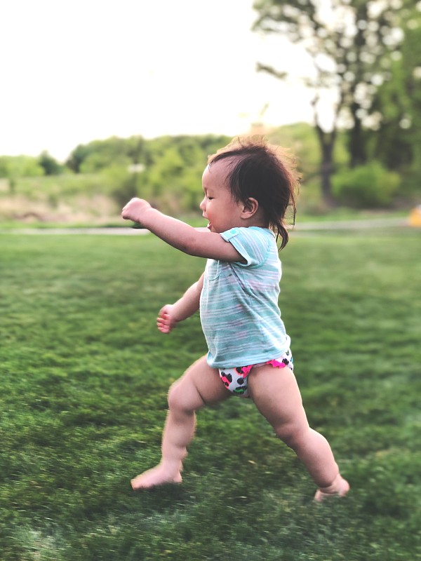 小女孩在公园的草地上奔跑图片素材