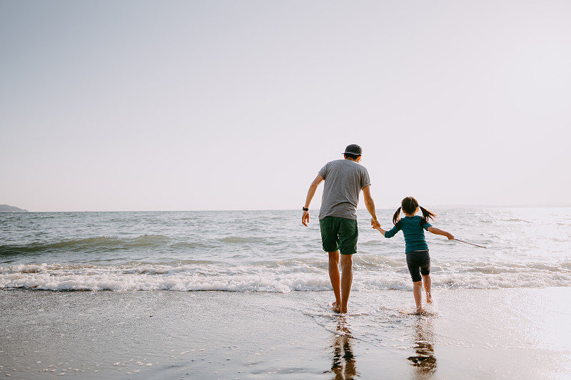 父亲和孩子在海滩上散步的后视图图片下载