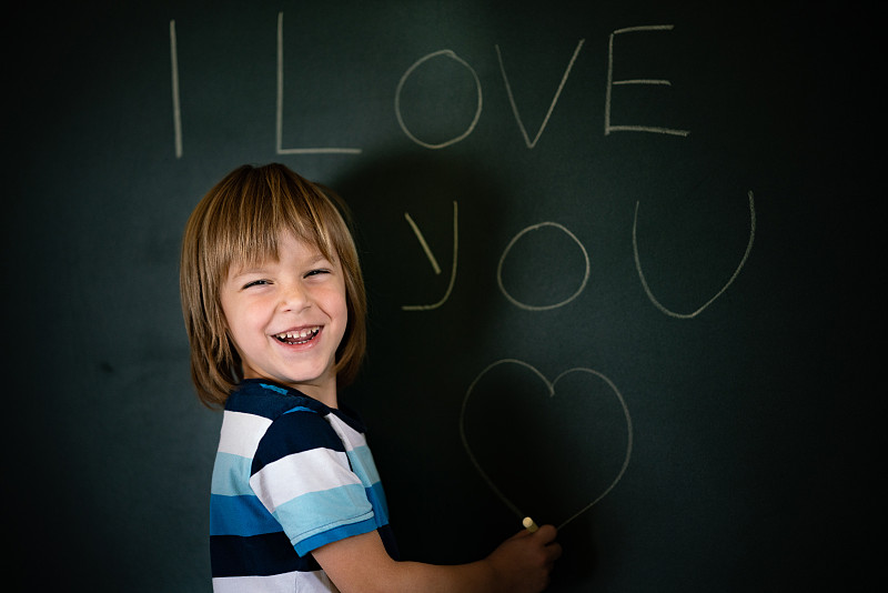 微笑的男孩在黑板上画画图片素材