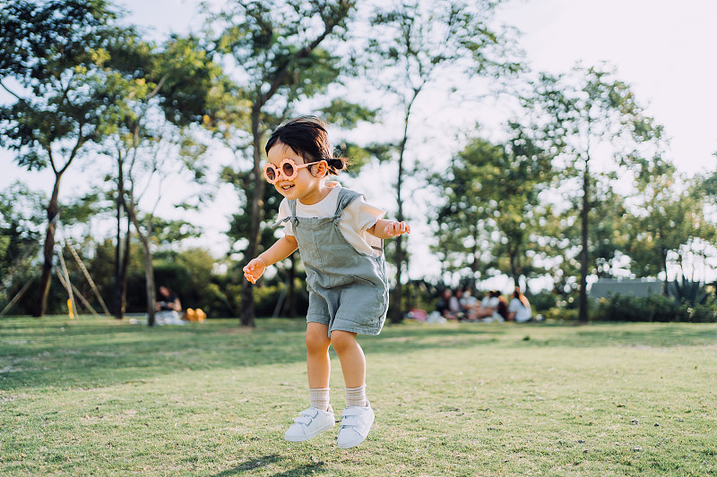 快乐的小亚洲学步女童与花形太阳镜在户外享受夏天在公园图片下载