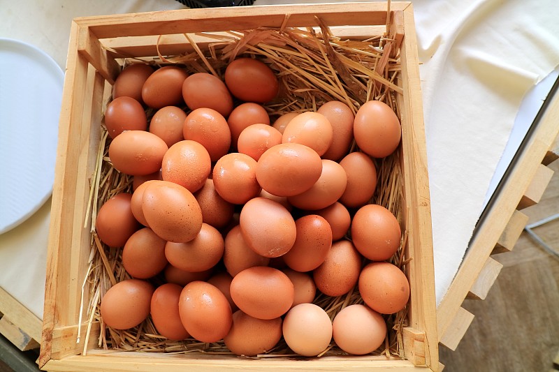 新鲜的棕色鸡蛋在木制的方形碗和干草。食物和物体概念。图片素材