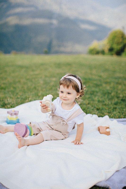 可爱的小女孩在山上的草地上玩彩色的木制玩具图片下载