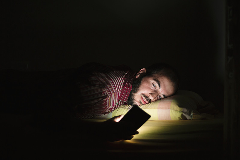 男人晚上躺在床上玩手机图片素材