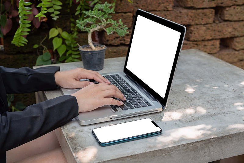 一位在户外花园使用笔记本电脑的亚洲女性。图片下载