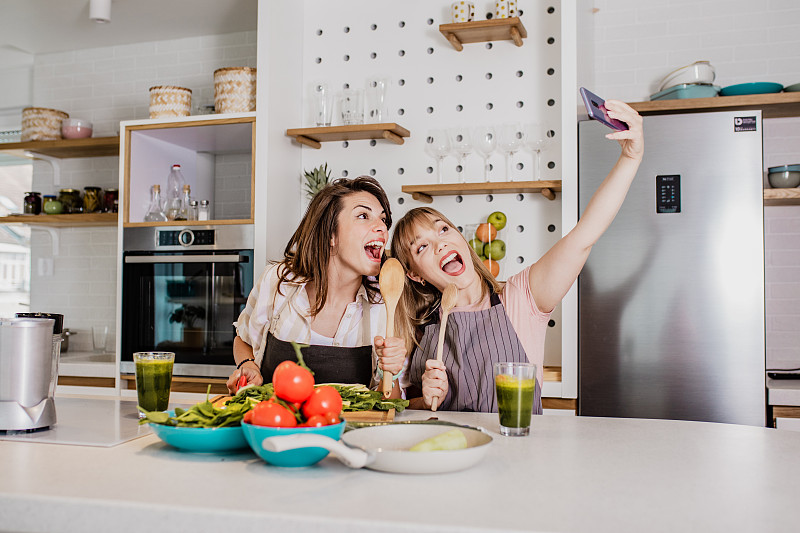 两个年轻的女性朋友在厨房里自拍图片素材