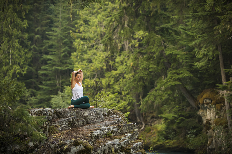 年轻女子练习瑜伽和冥想在森林设置。图片素材
